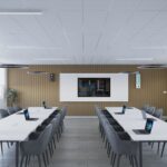 Sala institucional con mesas blancas, sillas ergonómicas y recursos tecnológicos para reuniones o formación académica.